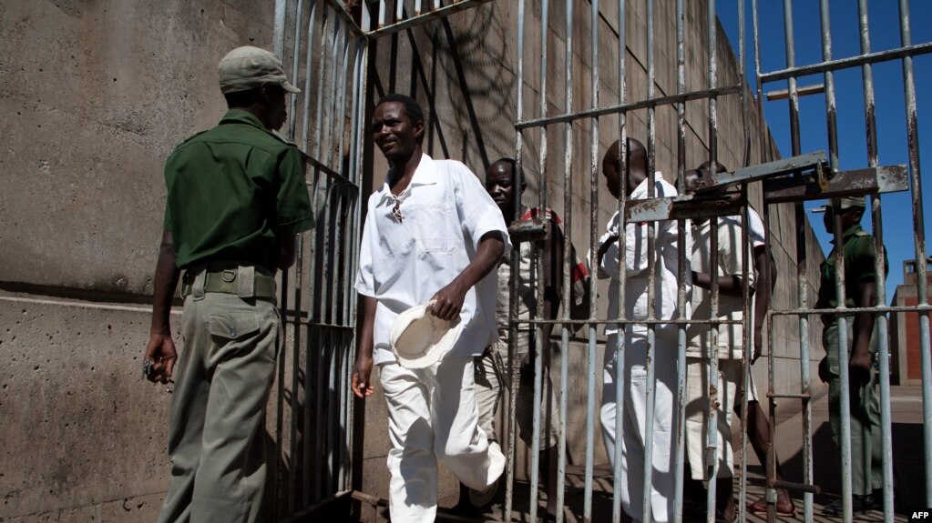 Vězni procházejí kolem vězeňské stráže ve věznici Chikurubi s maximální ostrahou v Harare, Zimbabwe, 20. května 2015 během prohlídky parlamentního výboru, aby zhodnotil stav národních věznic.